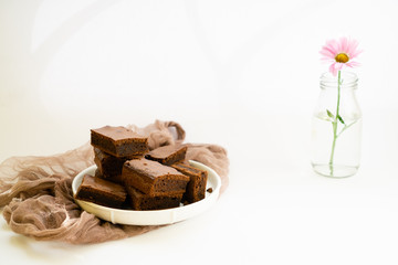 Chocolate brownie sliced into square slices on a white plate.