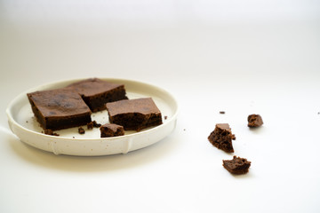 Chocolate brownie sliced into square slices on a white plate.