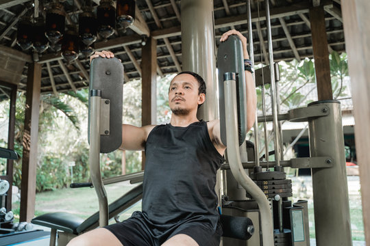 Asian man workout with pec deck machine in the gym house