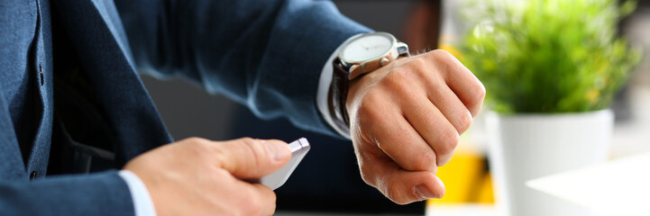 Man in suit and tie check out time at silver wristwatch closeup. Show and point with finger waste...