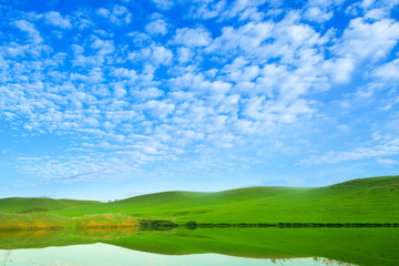 Morning on the lake with green hills and reflection