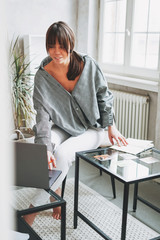 Working young brunette woman psychologist with laptop and associative cards near window at bright...
