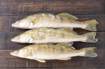 Fresh frozen freshwater fish on a dark wooden table. Top view, copy space, minimalist concept