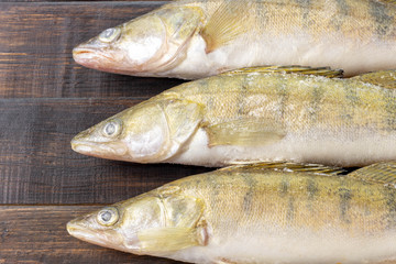 Fresh frozen freshwater fish on a dark wooden table. Top view, copy space, minimalist concept