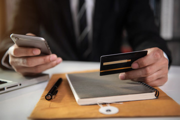 Male businessman use credit cards to conduct financial transactions through phones, tablet, and...