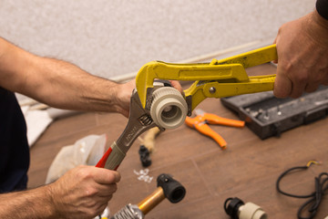 Plumber dropping a pipe with a wrench closeup.