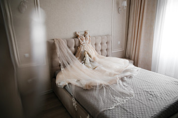 Fototapeta na wymiar wedding white dress lying on the bed on a white background with a decorative doll