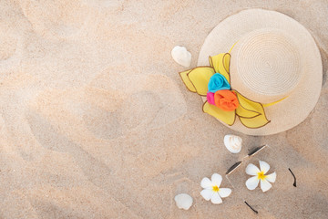 Top view of beach accessories with girl hat and shell on beach.