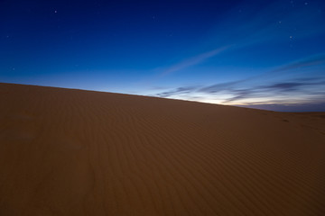 Fototapeta na wymiar night dramatic sky over sandy desert before sunrise