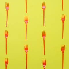 Plastic forks on yellow background.