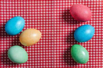 Multi-colored Easter eggs on a red checkered tablecloth.