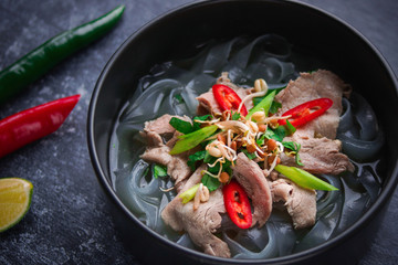 Asian cuisine, Vietnamese pho bo soup in a black plate on a dark background