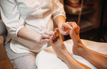 Obraz na płótnie Canvas Caucasian masseur is making a feet massage for the client during a spa procedure