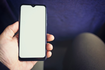 A man holds a modern smartphone in his hand when traveling on public transport