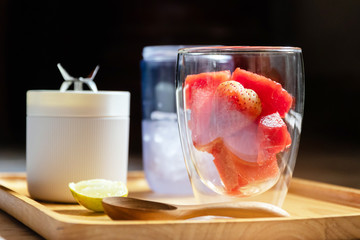 Healthy fruits with portable blender on wooden tray getting ready for making a smoothie. Fresh strawberry and watermelon with ice; healthy and fresh concept.