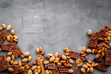 Sweets frame. Broken chocolate slices and nuts on grey stone background top-down copy space