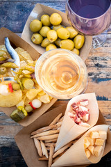 Tapas, pinchos, and wine. Cheese, jamon and olives, spicy gildas and potato chips, shot from above on a wooden table in an outdoors cafe