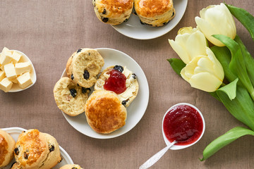 Scones with butter and jam on a brown background