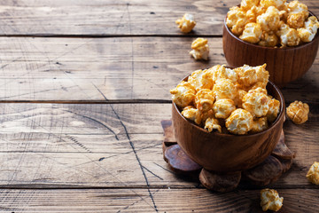 Popcorn in caramel glaze in wooden plates on a rustic table. Copy space.