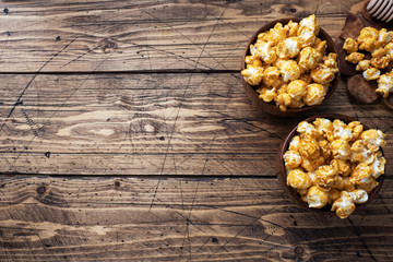 Popcorn in caramel glaze in wooden plates on a rustic table. Copy space.