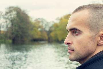 Man looks at the beautiful landscape, lake in the background, portrait, closeup, toned