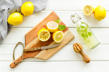 Make lemonade. Drink in bottle near utensil on white wooden background top-down