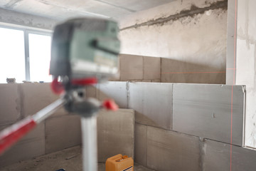 The construction worker Measures horizon level with a laser level. Construction of internal walls in the apartment using a plaster concrete plate with groove ridge. Gypsum plate