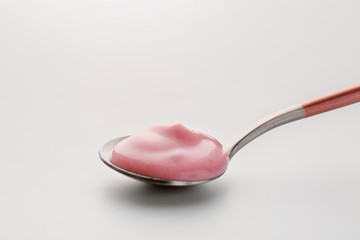 Spoon with fresh yogurt on white background