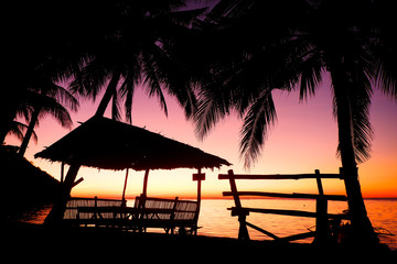 Silhouettes of bamboo hut and bench. Glowing sunset, Coron island, Philippines.