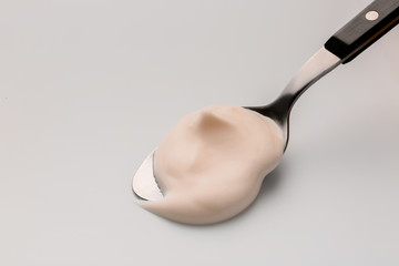 Spoon with fresh yogurt on white background