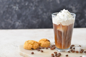 Glass of tasty iced coffee and cookies on table