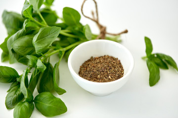 greens, culinary and flavoring concept - bunch of fresh basil herb and dry seasoning in cup on...