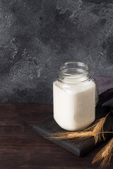 Glass jar with milk on a dark background. Copy space.