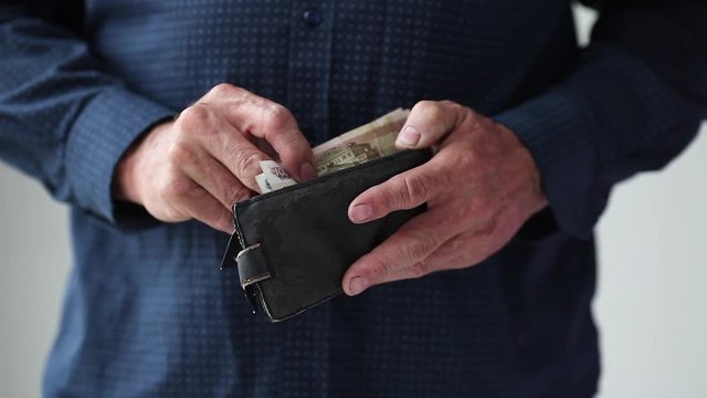 The hands of an adult man take 150 Russian rubles from an old wallet and show an empty wallet