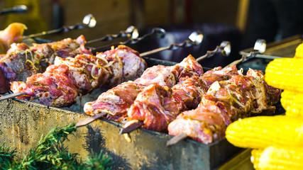 Grilling pork meat and sweet corn at street food stand outside