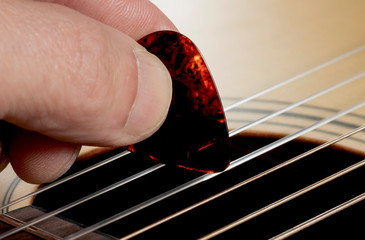 Guitarist plays guitar on wooden background, close up.