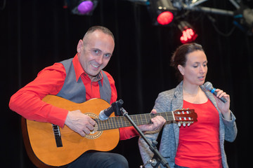 two people singing and playing guitar