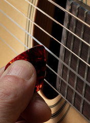 Guitarist plays guitar on wooden background, close up.