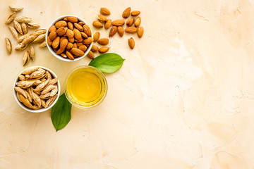 Almond oil - for cooking - in glass bowl near nuts on beige background top-down copy space