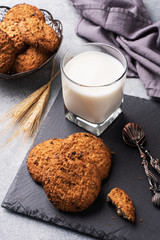 Homemade cookies cereals oats and a glass of milk on the grey concrete table.