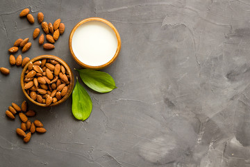 Almond milk near nuts on grey background top-down copy space