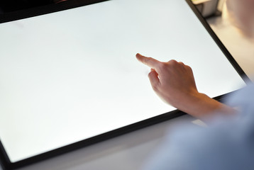 technology and people concept - hand on led light tablet or touch screen at night office