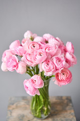 Spring background, flower Wallpaper. Persian buttercup. Bunch pink ranunculus flowers on light gray background. Vase on vintage wooden table. Wallpaper