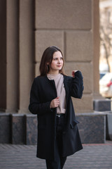 Portrait of a young woman walking around the city and looking around. Beautiful stylish woman walks along the street.