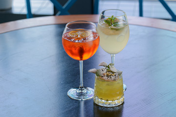 Three colorful refreshing cocktails served on a dark rustic wooden table with blurred background.
