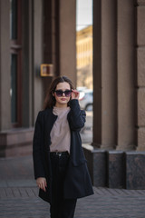 young woman in casual style and sunglasses on the city streets. Portrait of a beautiful stylish woman. vertical photo