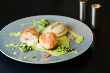 Cordon bleu chicken cutlet. Keiv cutlet with gravy and sauce served on a blue plate on dark rustic wooden table.