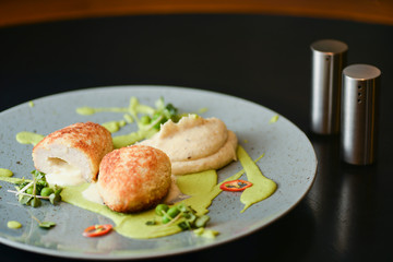 Cordon bleu chicken cutlet. Keiv cutlet with gravy and sauce served on a blue plate on dark rustic wooden table.