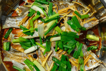 fresh steamed whole fishes covered with herbs onions and sauce