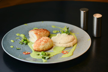 Cordon bleu chicken cutlet. Keiv cutlet with gravy and sauce served on a blue plate on dark rustic wooden table.